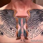 Фото тату: песочные часы с крыльями, украшенные надписью 'Memento Mori', выполнены в ярких цветах на груди.