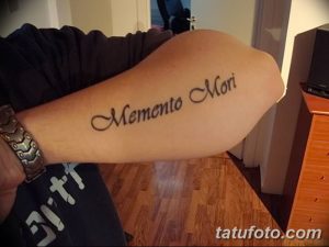 Фото тату с надписью 'Memento Mori', выполненной классическим шрифтом на руке. Стильная и элегантная татуировка, привлекающая внимание своей каллиграфией.