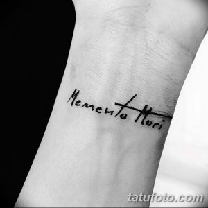 Фото тату с надписью 'Memento Mori', выполненной простым шрифтом на запястье. Стильная и минималистичная татуировка, привлекающая внимание своей лаконичностью.