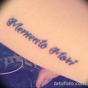 Фото тату с надписью 'Memento Mori', выполненной простым шрифтом на коже. Минималистичный и стильный рисунок татуировки, подходящий для тех, кто ценит лаконичность.