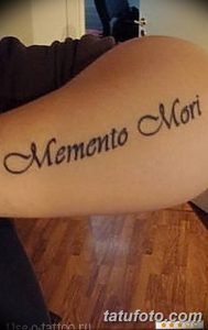 Фото тату с надписью 'Memento Mori', выполненной изящным шрифтом на коже. Простая, но элегантная татуировка, привлекающая внимание своей каллиграфией.