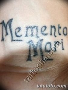 Фото тату надписи 'Memento Mori' черным цветом, выполненной на коже. Простой, но глубокий рисунок татуировки, подходящий для тех, кто ценит минимализм.