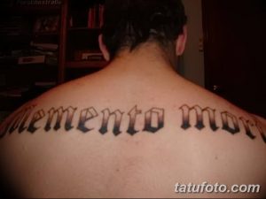 Фото тату надписи 'Memento Mori' в готическом стиле на спине. Черный рисунок татуировки выглядит мощно и выразительно.