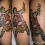 Фото тату Leatherface с бензопилой на руке. Реалистичный рисунок татуировки персонажа из фильма ужасов, выполненный в ярких цветах.