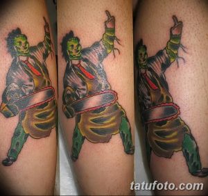 Фото тату Leatherface с бензопилой на руке. Реалистичный рисунок татуировки персонажа из фильма ужасов, выполненный в ярких цветах.
