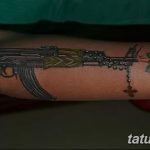 Фото тату: татуировка автомата Калашникова с букетом роз и четками на руке, выполненная в реалистичном стиле.