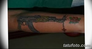 Фото тату: татуировка автомата Калашникова с букетом роз и четками на руке, выполненная в реалистичном стиле.
