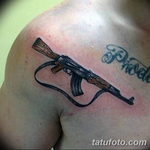 Фото тату автомата с ремнем, расположенного на плече. Черно-серый рисунок с реалистичной проработкой деталей. Подходит для любителей военной тематики.