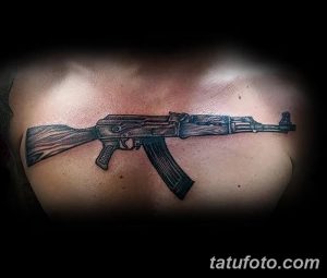Фото тату автомата, выполненного на груди. Детализированный черно-серый рисунок, демонстрирующий мощь и реалистичность. Подходит для мужчин, ценящих брутальные мотивы.