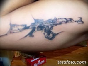 Фото тату размытого автомата Калашникова на руке. Нечеткий рисунок татуировки, выполненный в черно-серых тонах, эффект акварели.