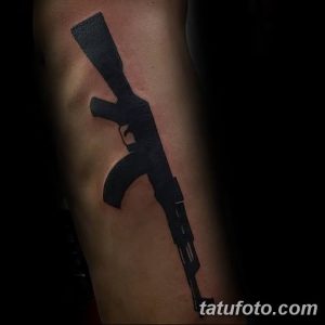 Фото тату черного автомата Калашникова на предплечье. Минималистичный рисунок татуировки, выполненный в технике blackwork, четкие линии и контуры.