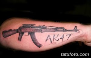 Фото татуировки автомата Калашникова с надписью 'AK47', выполненной в реалистичном стиле на предплечье.