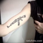 Фото тату: реалистичный рисунок автомата Калашникова на предплечье. Черно-белая татуировка с высокой детализацией.