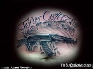 Фото тату автомата Калашникова на груди с надписью 'Hijo Corazon'. Рисунок выполнен в реалистичном стиле с использованием черных и серых оттенков.