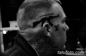 Фото татуировки на голове, изображающей автомат Калашникова и надпись 'LYRICAL ASSAULT'. Черно-белый рисунок.