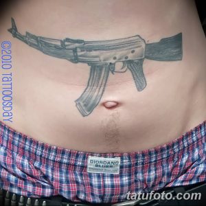 Фото тату автомата Калашникова, расположенного на животе мужчины. Черно-серый рисунок, выполненный в реалистичном стиле.