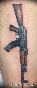 Фото реалистичной татуировки автомата Калашникова на руке. Детализированный рисунок оружия с использованием коричневых и серых оттенков.