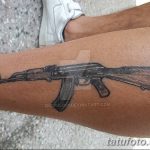 Фото тату на икре: реалистичное изображение автомата Калашникова, выполненное в черно-коричневых тонах. Детализированный рисунок татуировки.