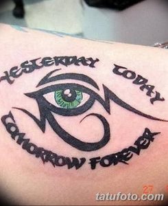 Фото тату Глаз Гора с надписями "Yesterday", "Today", "Tomorrow", "Forever" и зеленым зрачком. Оригинальный рисунок татуировки на руке.