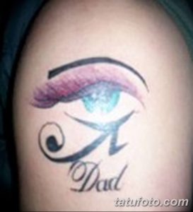 Фото тату Глаза Гора с розовыми акцентами и надписью "Dad" на плече. Татуировка выполнена в ярких, но нежных тонах.