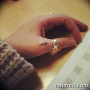Фото тату: небольшой рисунок на пальце руки. Минималистичный рисунок татуировки, выполненный в темных тонах.