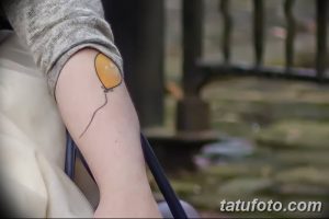 Фото минималистичной татуировки в виде желтого воздушного шарика на руке. Простой, но очаровательный рисунок, выполненный тонкими линиями.