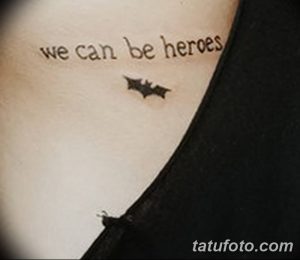 Фото тату с надписью 'we can be heroes' и маленьким изображением силуэта Бэтмена. Черно-белая татуировка на плече, символизирующая силу и надежду.