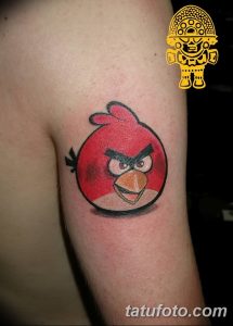 Фото татуировки персонажа Angry Bird, красной птицы, на бицепсе. Яркий и забавный рисунок татуировки для фанатов игры.