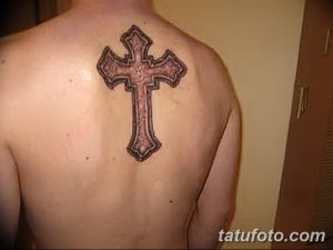 Фото классической татуировки креста на спине мужчины. Черно-серый рисунок татуировки с четкими контурами и объемными тенями.