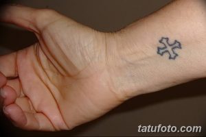 Фото минималистичной тату креста на запястье. Изображение выполнено в синих тонах с использованием тонких линий.