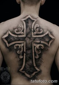 Фото большой тату креста на спине в стиле blackwork. Изображение выполнено в черно-белых тонах с использованием сложных узоров и теней.