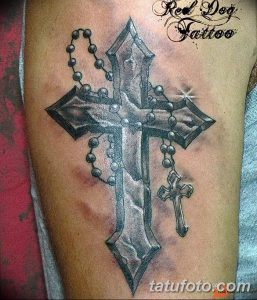 Фото тату креста с четками на руке в реалистичном стиле. Черно-серый рисунок татуировки с детальной проработкой текстур и теней.
