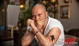 Фото минималистичной татуировки креста на руке. Простой черно-серый рисунок татуировки с четкими линиями и лаконичным дизайном.