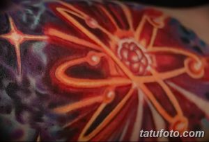 Детализированная татуировка атома на фоне космического пейзажа, выполненная в ярких и огненных цветах. Оригинальный и эффектный рисунок тату.