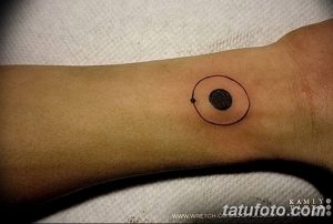 Фото простой татуировки на запястье: черная точка внутри красного круга. Минималистичный дизайн для любителей лаконичных рисунков.