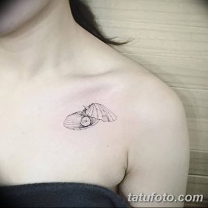 Фото минималистичной татуировки ракушки с жемчужиной на ключице. Тонкие линии и черно-белый рисунок.