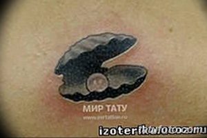 Фото тату: небольшая черно-серая татуировка раковины с жемчужиной на коже. Простой и элегантный рисунок татуировки.