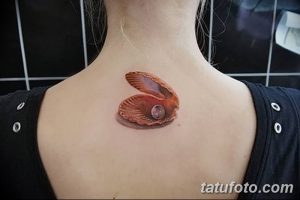 Фото тату: небольшая раковина с жемчужиной на спине девушки. Детализированный рисунок татуировки в реалистичном стиле.