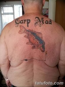 Фото тату карпа кои и надписи "Carp Mad" на спине. Яркие цвета, юмористический стиль. Эскиз татуировки для любителей рыбалки.