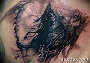 Фото тату Жнеца на плече, выполненное в черно-серых тонах. Детализированный рисунок с мрачным выражением лица.