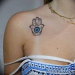 Фото татуировки Хамса на плече девушки. Черно-белый рисунок с изображением глаза и узоров. Идеально подходит для тех, кто ищет идеи для небольших и изящных татуировок.