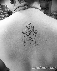Фото тату Хамса на спине, выполненная в технике blackwork. Лаконичный рисунок с тонкими линиями и точечными элементами.