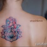 Фото тату Хамса на спине, выполненная в акварельной технике с использованием розовых, голубых и бирюзовых оттенков. В центре композиции - цветок лотоса и глаз.