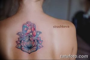Фото тату Хамса на спине, выполненная в акварельной технике с использованием розовых, голубых и бирюзовых оттенков. В центре композиции - цветок лотоса и глаз.