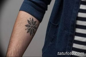 Фото тату: маленькая черная снежинка на предплечье, выполненная в минималистичном стиле. Изящный рисунок татуировки для девушек и парней.
