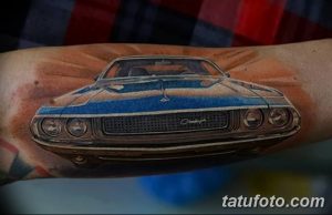 Фото тату на руке с изображением автомобиля Dodge Challenger в ярких цветах. Детализированный рисунок татуировки с эффектом солнечного света.
