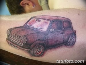 Фото тату на предплечье с изображением классического Mini Cooper в бордово-коричневой гамме. Детализированный рисунок татуировки выполнен в реалистичном стиле.