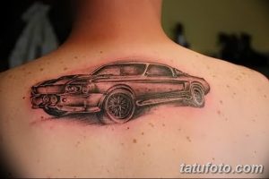 Фото тату на спине с изображением классического автомобиля Ford Mustang в серо-черной гамме. Детализированный рисунок татуировки выполнен в реалистичном стиле.