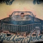 Фото тату классического автомобиля с розами и надписью в стиле old school на животе. Рисунок выполнен в черно-серых тонах.