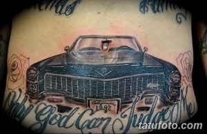 Фото тату классического автомобиля с розами и надписью в стиле old school на животе. Рисунок выполнен в черно-серых тонах.